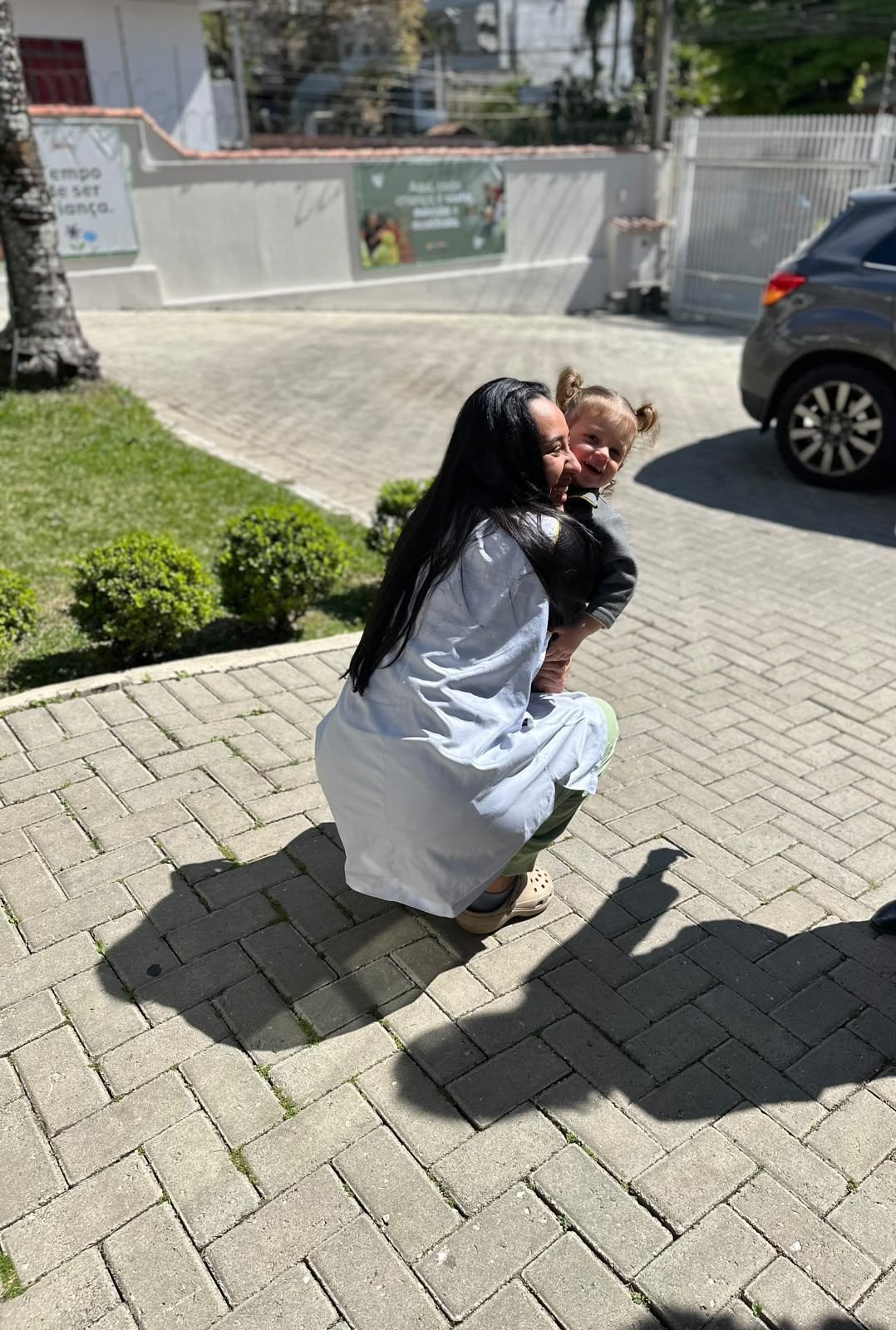 Educadora abraçando uma criança na entrada da escola